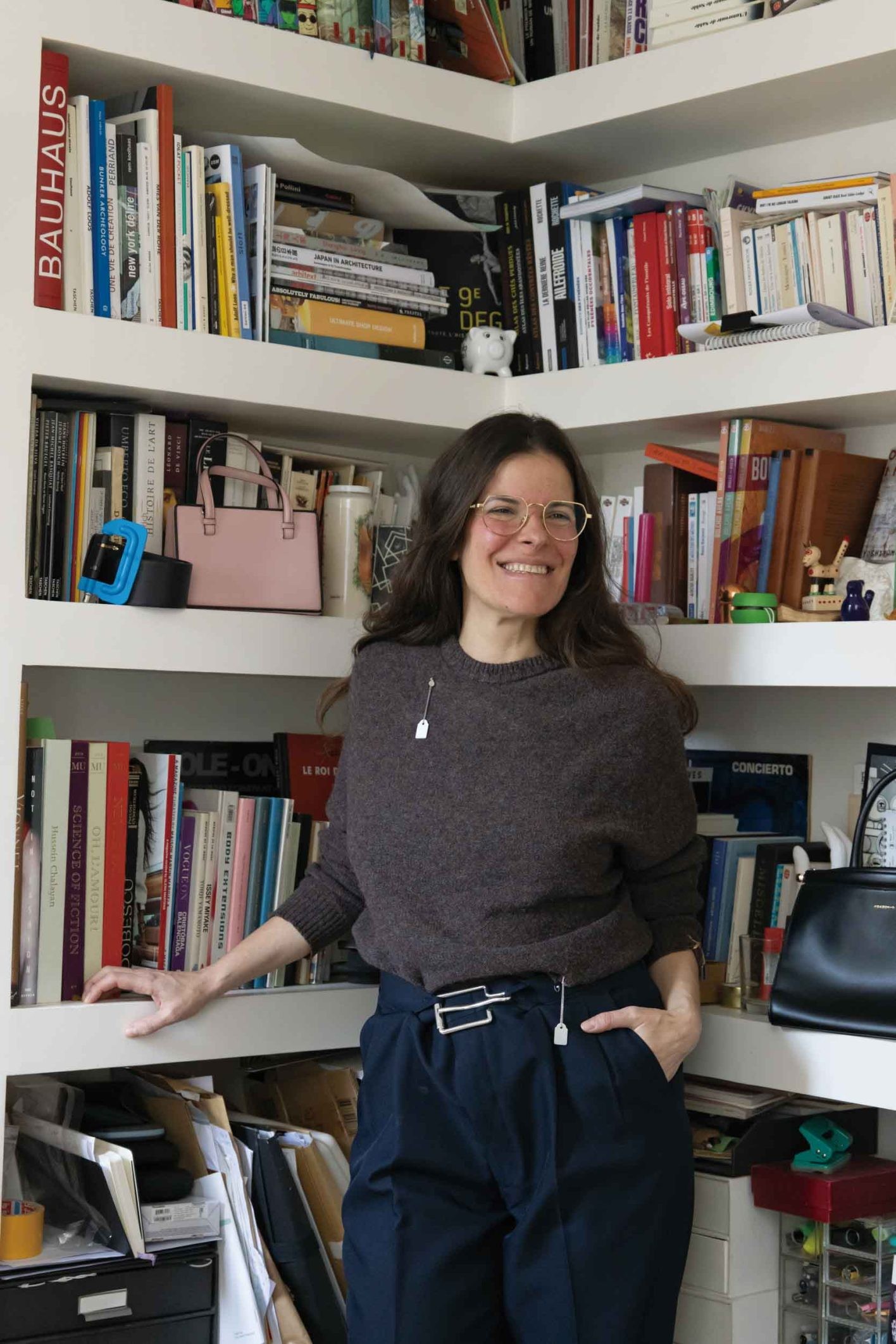 本棚も小物やバッグのディスプレイに活用。ニットの穴にタグ型のジュエリーをあしらいチャーミングに。オーバーサイズのパンツにはサイズ調整可能なブローチを。