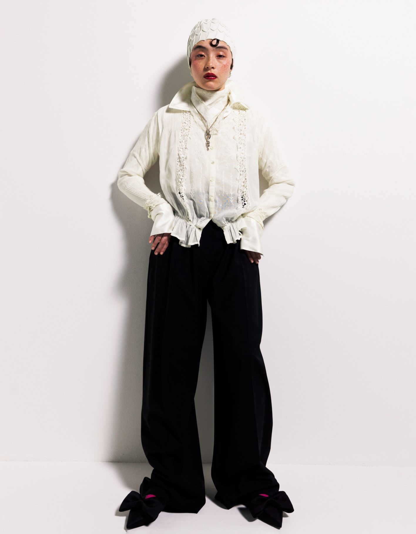 透け感のある古着の白、光沢のある今の白、懐かしいリネンの白、頭にかぶったラバーの白。質感の違う白を重ねる。アンティークのブラウス ¥41,800（トロ）／中に着た白のシルクジップシャツ ¥60,500（ケイスケヨシダ | ケイスケヨシダ カンパニー・リミテッド）／首に巻いた古いリネンハンカチ ¥4,830（ジャンヌ バレ）／パンツ ¥134,200（スポーツマックス | マックスマーラ ジャパン）／スイムキャップ ¥6,800（ワッフルハウス）／シルバーのペンダント ¥623,700（エルメス | エルメスジャポン）／リボンシューズ ヒール1cm ¥94,900（キムへキム | カーブストア）／ソックス＊スタイリスト私物