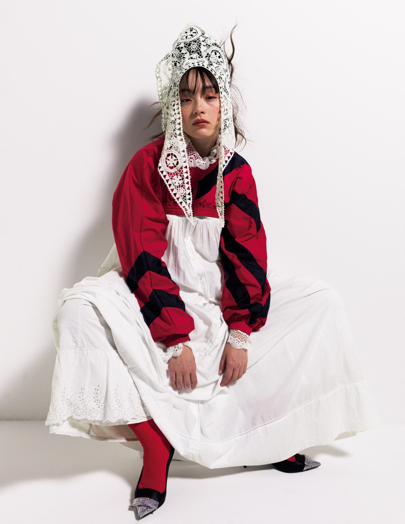 アンティーク・ホワイトのアイコンでもあるワンピースには、ショート丈ブルゾンを重ねる&amp;スカートの重ねばきで、白のボリューム感を強調。赤のクロップドジャケット ¥65,450（ヴァケラ | ドーバー ストリート マーケット ギンザ）／中に着たアンティークのワンピース ¥96,800（トロ）／下に重ねた古着スカート ¥23,100（ジャンヌ バレ）／頭にかけている付け襟 ¥17,800（ワッフルハウス）／パンプス ヒール9cm ¥188,300＊参考価格（セルジオ ロッシ | セルジオ ロッシ ジャパン カスタマーサービス）／ハイソックス＊スタイリスト私物