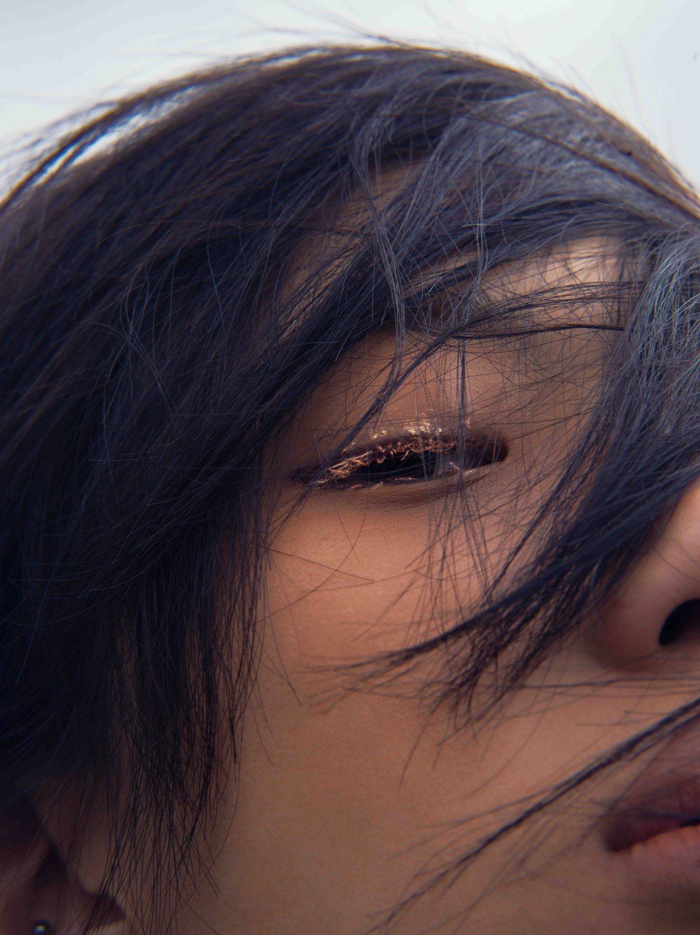 「季節を味わうように、メイクで遊んでみるのも楽しいと思います。冬の景色と一体化する、ニュートラルなワントーンの綺麗さ。あえて色をのせないという選択の面白さを知る、きっかけになるかもしれません」（UDAさん）。目を柔らかく縁取る、ゴールドの睫毛が印象的。使用したのは、〈COCOROIKI〉のカラーパールマスカラ「ローズゴールド」（¥1,500＊編集部調べ）。