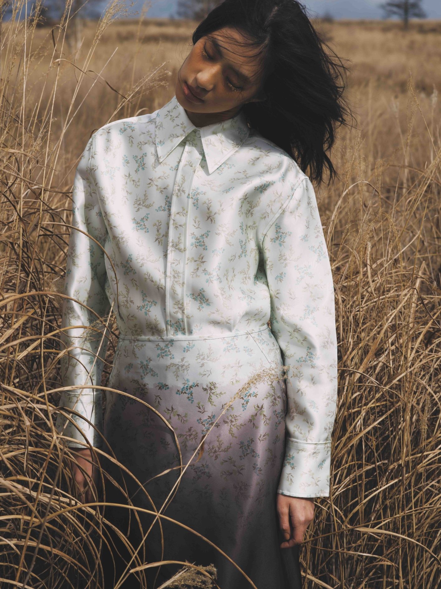 「小花柄が褪せたグラデーションへと美しく流れていく様子が、まるで移り変わる季節のよう」（井伊さん）。闇から光へ、希望に対する願いを込めた〈ジル サンダー〉のコレクション。優雅な光沢のシルク混の生地の上で、漆黒がゆっくりと明るみ、可憐なブーケが浮かび上がる。シャツ ¥404,800、スカート ¥327,800（共にジル サンダー | ジルサンダージャパン）