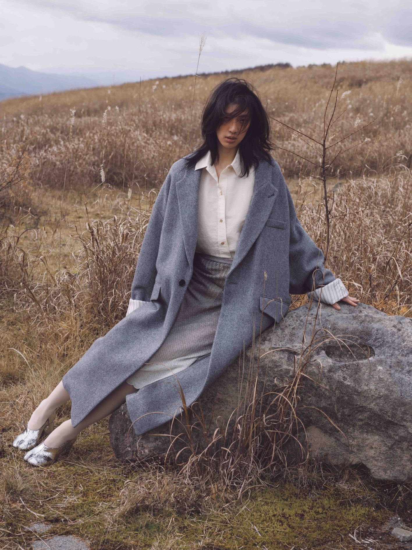 ふわりと身体を包み込むような丸いシルエットで仕立てられた、〈メゾン マルジェラ〉のウールコート。折り返した袖から現れる、ストライプの裏地もアクセント。「コートの袖幅が広いからか、どことなく打掛のような風情もありますね」（井伊さん）。コート ¥479,600、シャツ ¥209,000、スカート ¥229,900、シューズ ヒール8cm ¥209,000（以上メゾン マルジェラ | マルジェラ ジャパン クライアントサービス）／タイツ ＊スタイリスト私物