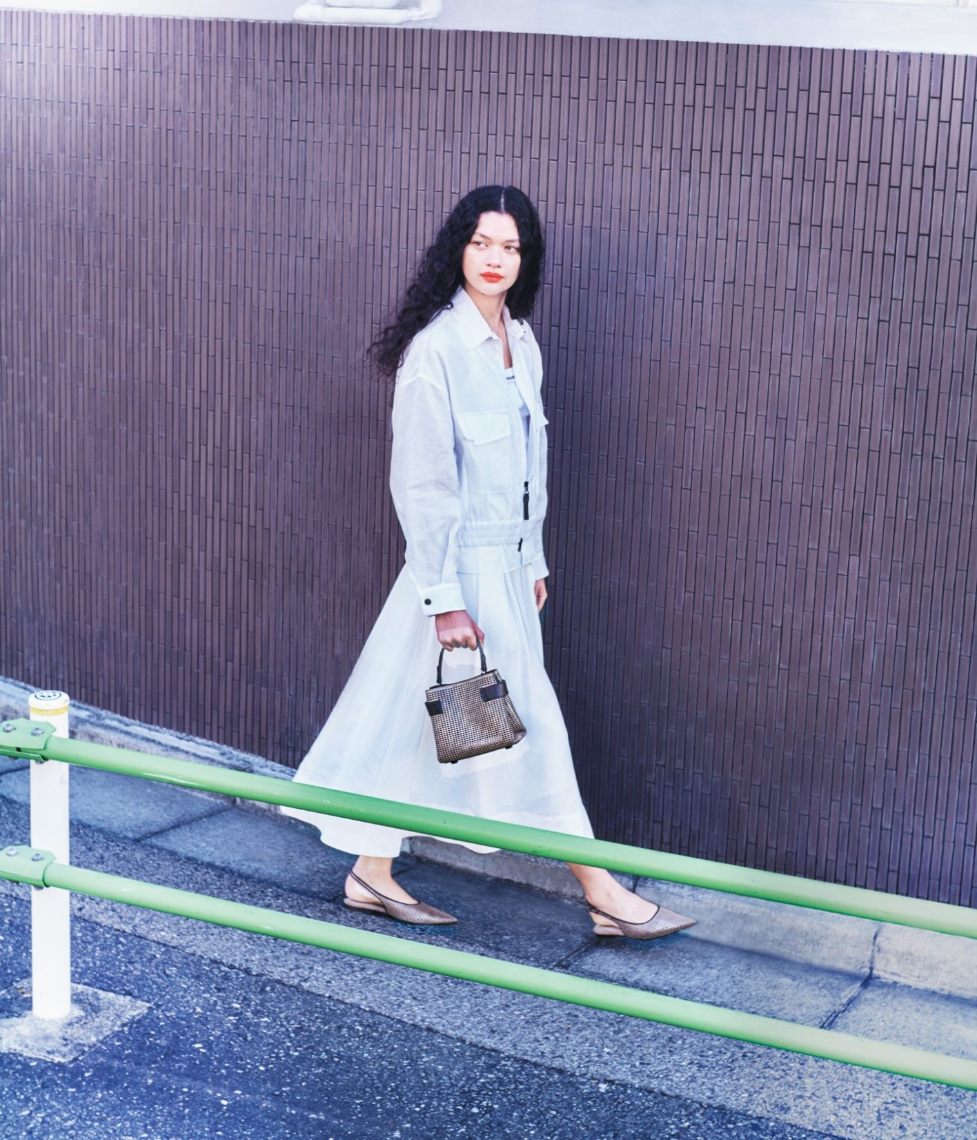 優雅なスクエアラインを描く〈Essence〉。今シーズンはメタリックレザーにレーザーカットを施した、 軽やかなマテリアルとして新たに登場。幾何学的なフォルムに、「モニーレ」を刺繡したインサートがよく映える。取り外し可能なショルダーストラップ付き。バッグと同じマテリアルのパンプスを添えて、足元でさりげないリンクを。バッグ〈Essence〉H17 ×W19×D9cm ¥543,400、ジャケット ¥649,000、中に着たタンクトップ ¥156,200、スカート ¥390,500、パンプス ヒール1cm ¥203,500（以上ブルネロ クチネリ | ブルネロ クチネリ ジャパン）