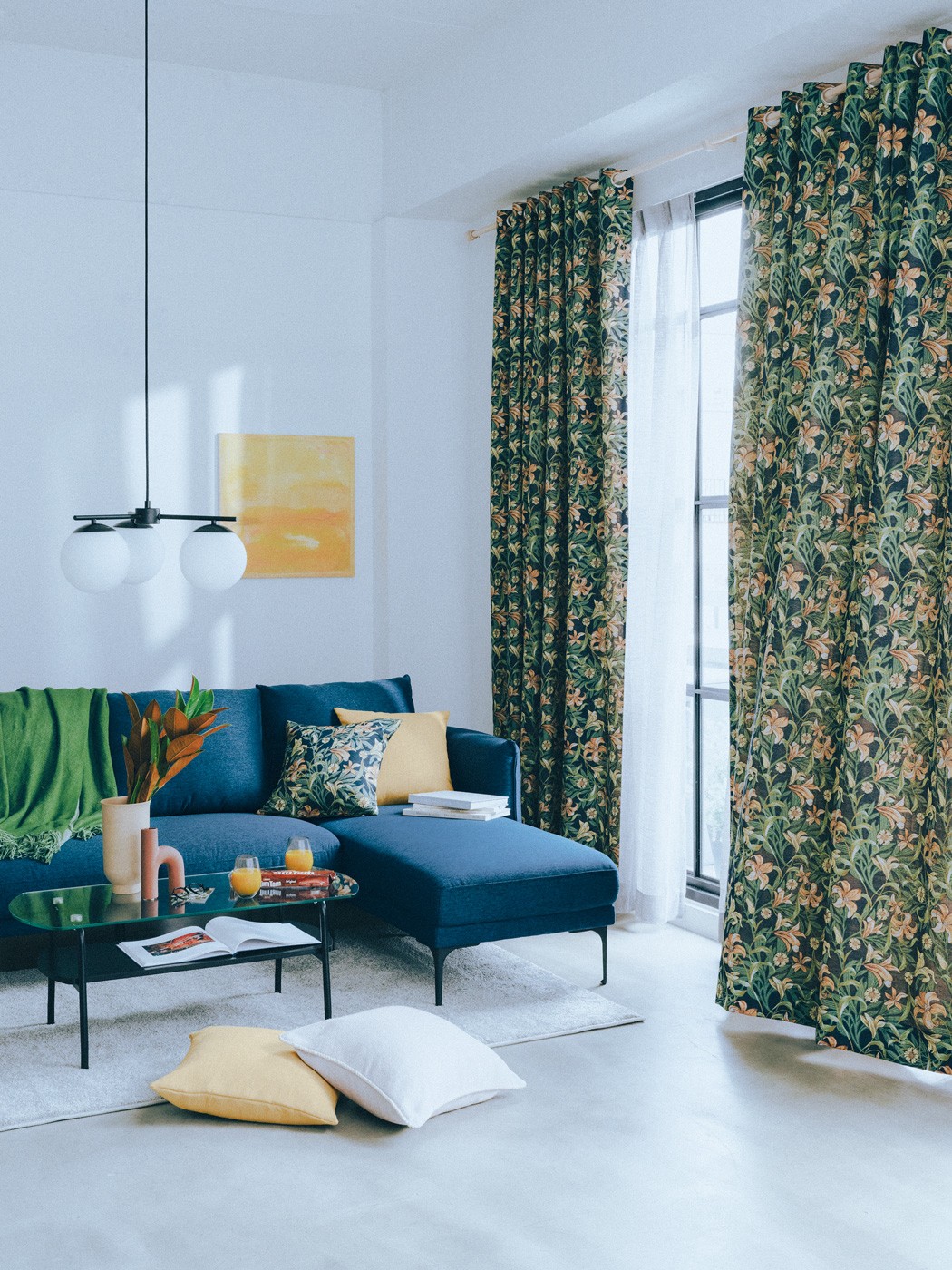 オーダードレープカーテン ハトメ*2枚入り H265×W225cm¥66,000、オーダーレースカーテン 2倍ヒダ*2枚入り H248×W160cm¥21,000、カーテンレールダブル W166〜312cm¥6,990、左カウチソファ H 85×W214×D162cm¥99,900、ソファ上のオーダークッションカバー 各¥1,490、センターテーブル H38×W95×D45cm¥11,900、タンブラー 各¥899、ラグ 約133×190cm¥9,990、手前のクッションカバーパイピング加工 ホワイト¥1,990、オーダークッションカバー イエロー¥1,490