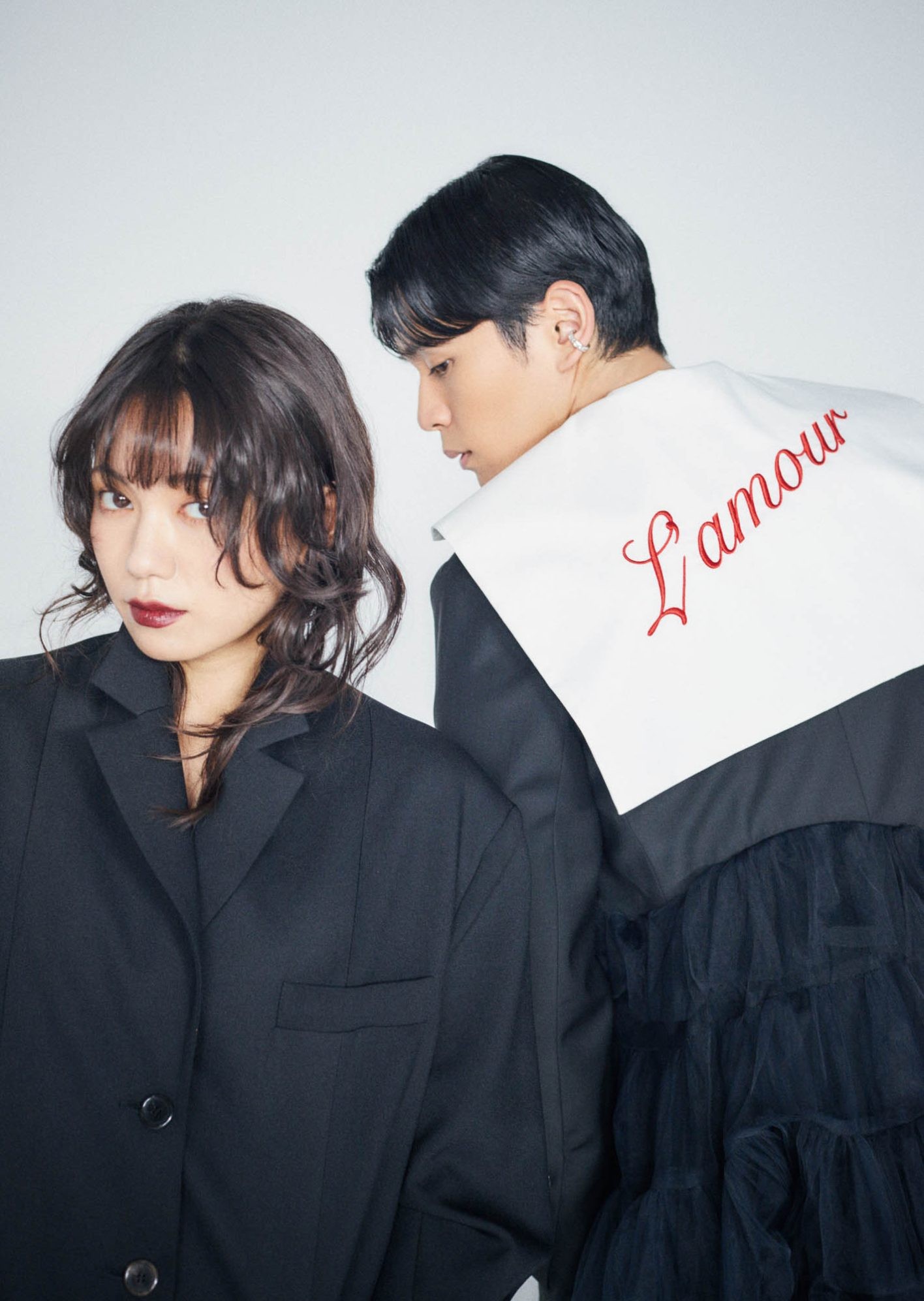 二階堂さんは、仕立てが美しい〈ガディッド アノニム〉のオーバーサイズ。ワンピースのように潔く1枚で。眞栄田さんは、幾重にもチュールが彩る〈ヴィヴィアーノ〉を。セーラーカラーにのせられた真紅の刺繡のフレーズも情熱的。ともにジェンダーや立場に関係なく、身につける人をエンパワーメントするブランドのジャケットを鍵に、端麗なモノトーンで。二階堂さん ジャケット ¥35,200(ガディッド アノニム | ピーアールワントーキョー)/レースのタイツ ¥9,900(ウォルフォード | リトルリーグ インク)/パンプス ヒール8.5cm ¥18,700(イエロ) 眞栄田さん ジャケット ¥115,500、セーラーカラーシャツ ¥57,200、パンツ ¥79,200(以上ヴィヴィアーノ)/シューズ ¥143,000(クリスチャン ルブタン | クリスチャン ルブタン ジャパン)/イヤリング ¥26,400、ブレスレット ¥27,500(共にノウハウ | ノウハウ ジュエリー)