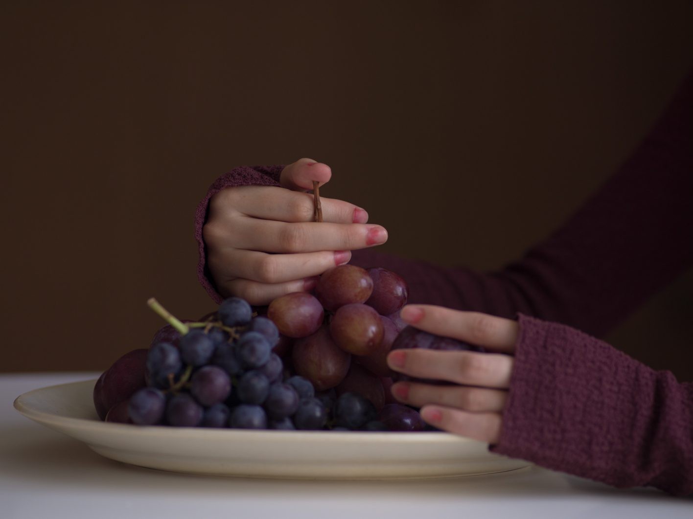 肌あたりが優しいリサイクルポリエステル100%のボディスーツ。ぴったりとフィットし、ボディラインを彫刻のように際立たせる。「とてもフォトジェニックで、存在感を放つ服」(井伊さん)。「思いがけず果実の汁で染まってしまったかのような遊びを指先に」(UDAさん)。既成のマニキュアを薄めてつくった桜貝色をポンポンとラフに重ね、上からマットコートを。ボディスーツ ¥71,500(イッセイ ミヤケ)