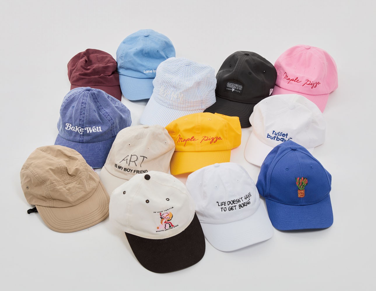 最近整理したキャップの一部。ツバが黒いものは、昨年鵠沼の飲み屋で出会った男性の自作。隣の白い帽子はスタイリストの長谷川昭雄さんがディレクションしたスヌーピー展のグッズ。チャーリー・ブラウンの名言「人生に退屈する必要はないもんね」が刺繡されている。仕事が縁でファンになったジャイアンツの黒の帽子はロゴが控えめで使いやすい。