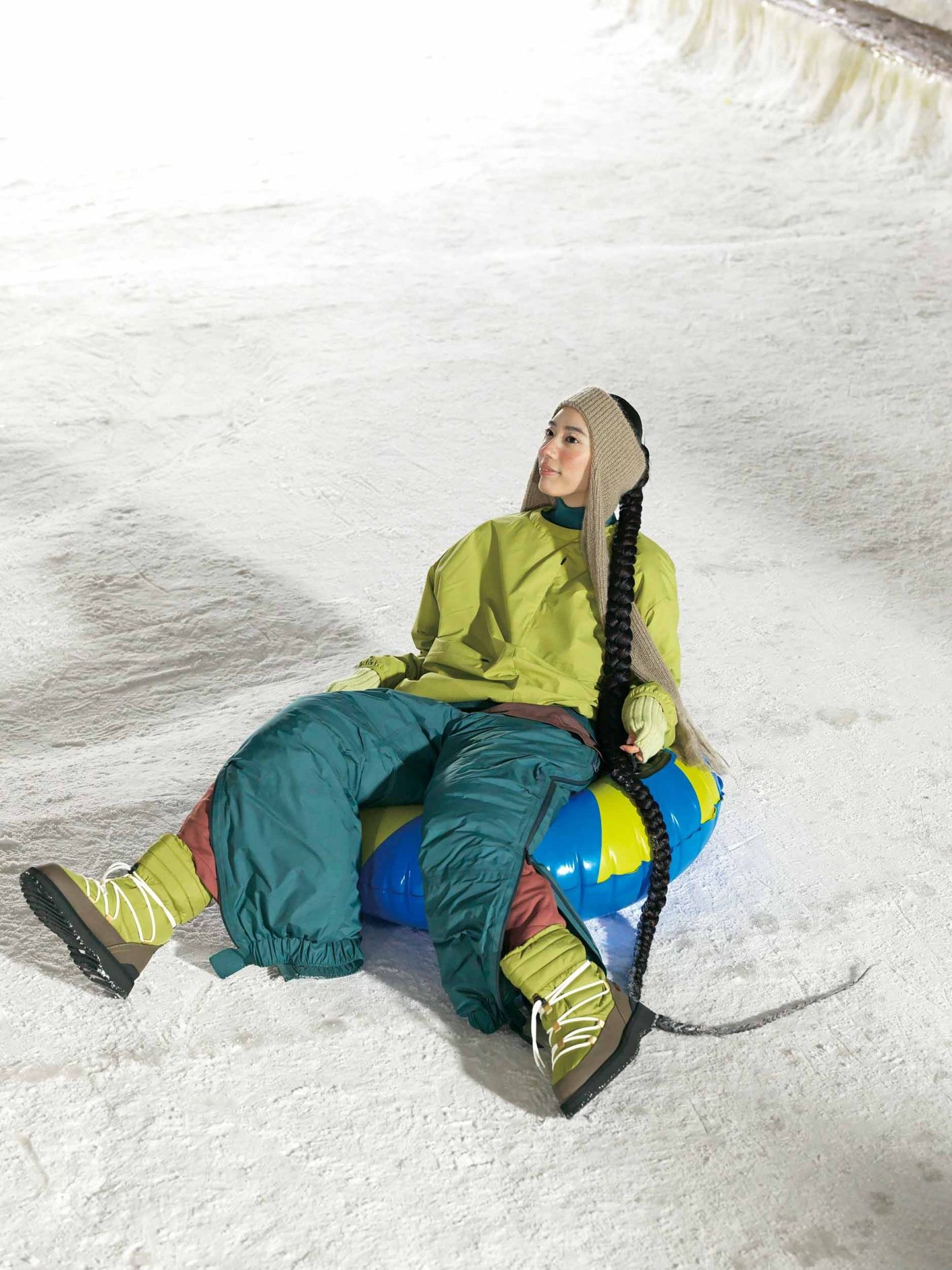 浮き輪みたいなポップなソリで滑る日は、グリーンを基調に茶色を効かせ、全身落ち着いたアーストーンに。上はアウトドアに最適な吸水速乾に優れたプルオーバーを加えた3枚重ね。極寒地でも頼れるダウンパンツの下に、中綿入りのパンツを忍ばせれば、防寒対策もばっちり。両サイドのファスナーを開けて、ちらりと裾を覗かせて。トップ ¥28,600、中に着たタートルネック ¥20,900、中に着たカットソー ¥12,100、パンツ ¥88,000、中に着たパンツ ¥24,2 00(以上スノーピーク)/ヘッドアクセ ¥ 34,000、アームウォーマー ¥18,000(共にキジマ タカユキ | サカス ピーアール)/スノーシューズ ¥36,300(スイコック)