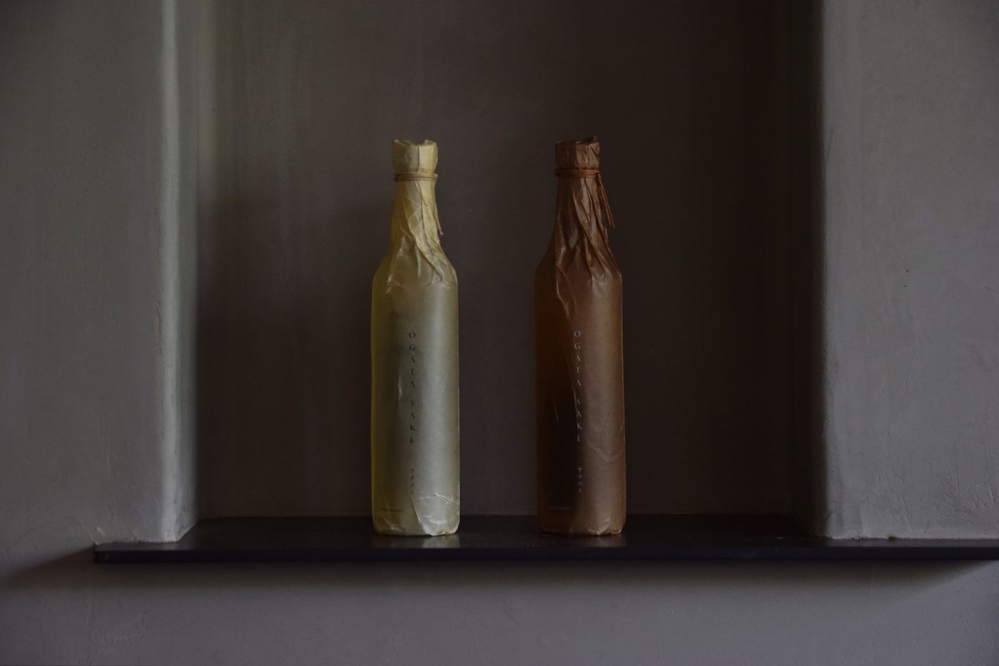 「ワタツミ」「ヤマツミ」それぞれのボトルは、酒の色合いを思わせる蝋引き紙で包まれ、ラベルの裏面には、海や山の情景を映すイメージがあしらわれている。